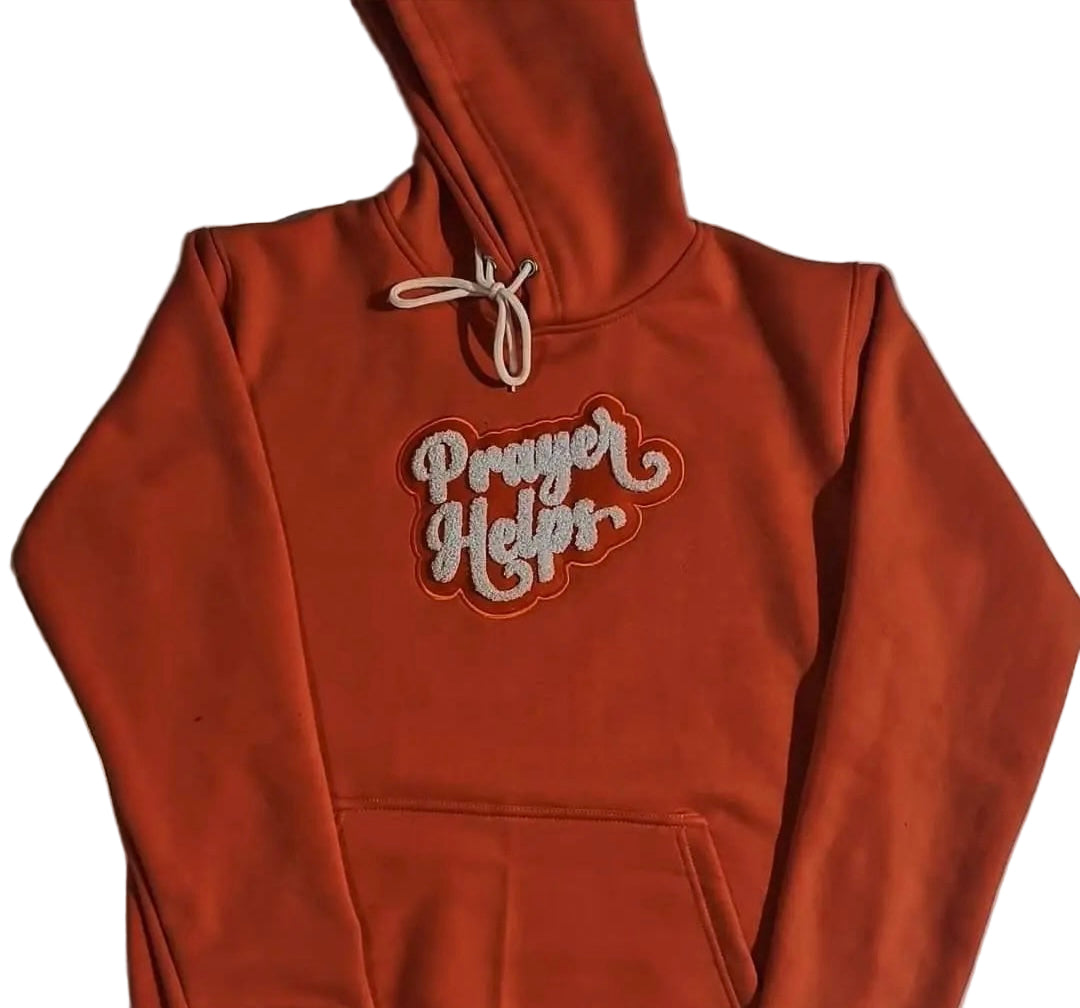 Orange hoodie with 'Prayer Helps' text on a light gray background