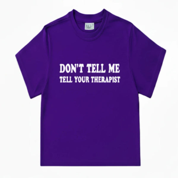 A purple short-sleeve crewneck t-shirt with the text 'DON'T TELL ME TELL YOUR THERAPIST' in white letters