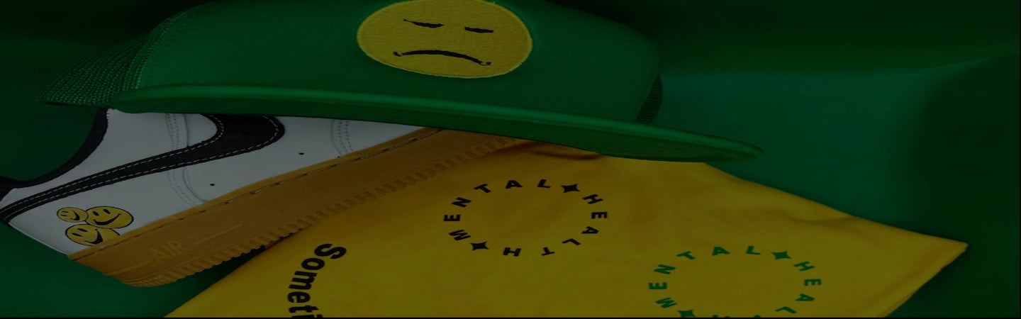 A green baseball cap with a yellow sad face patch.